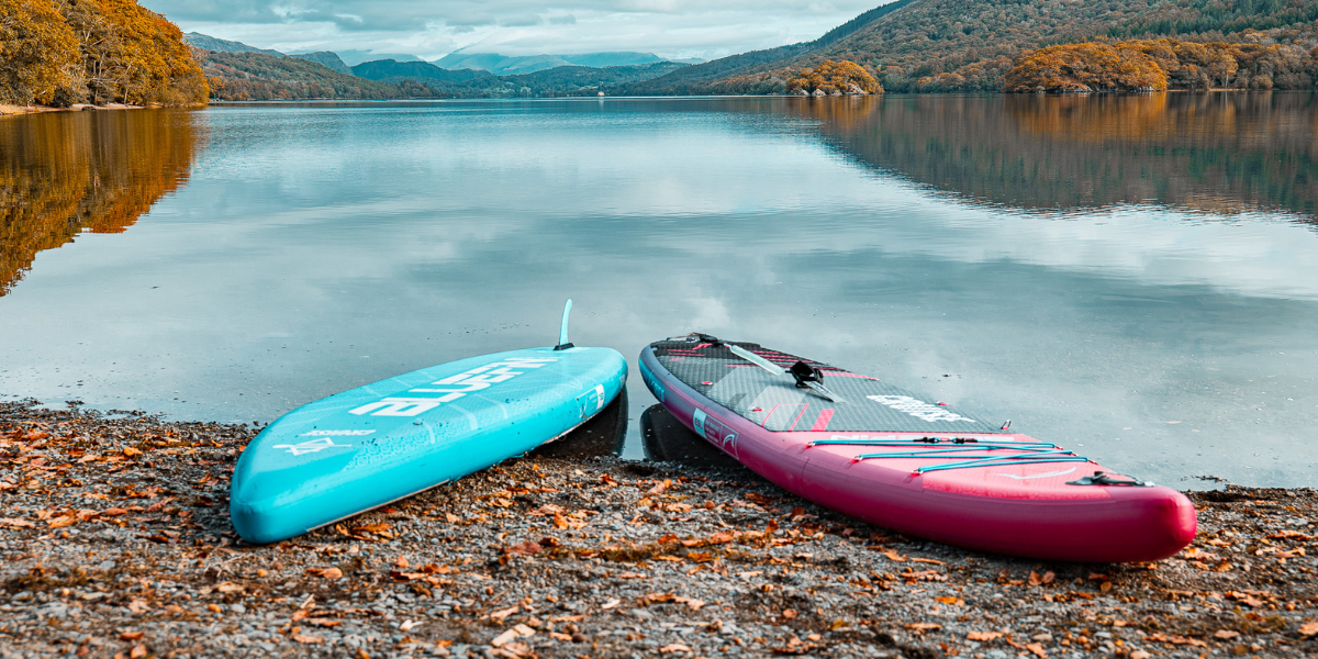 two paddleboards on a lake front with the backdrop of autumn leaves