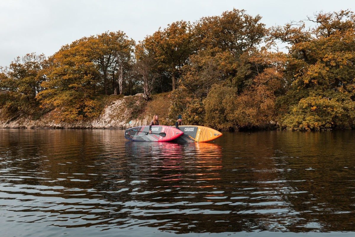 two people holding paddleboards in the middle of the lake