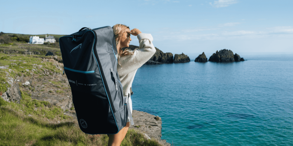 woman looking out to sea with SUP backpack 