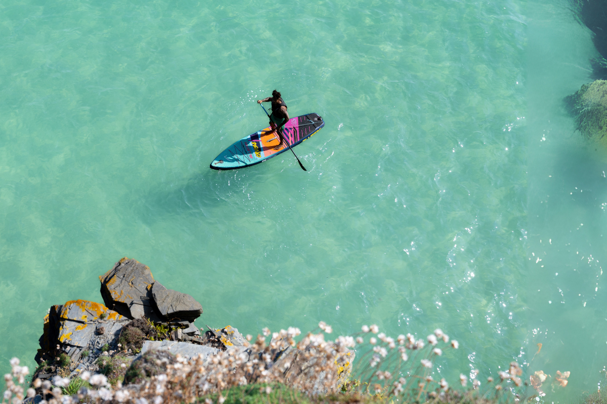 man paddleboarding on the ocean with clear water