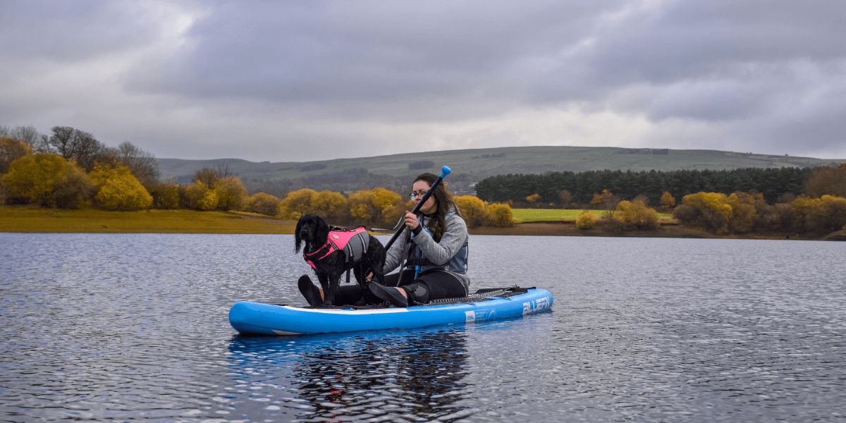 woman paddleboarding with dog