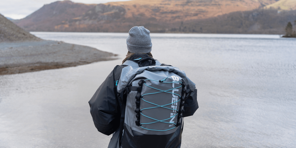 looking out onto water with paddleboard in backpack
