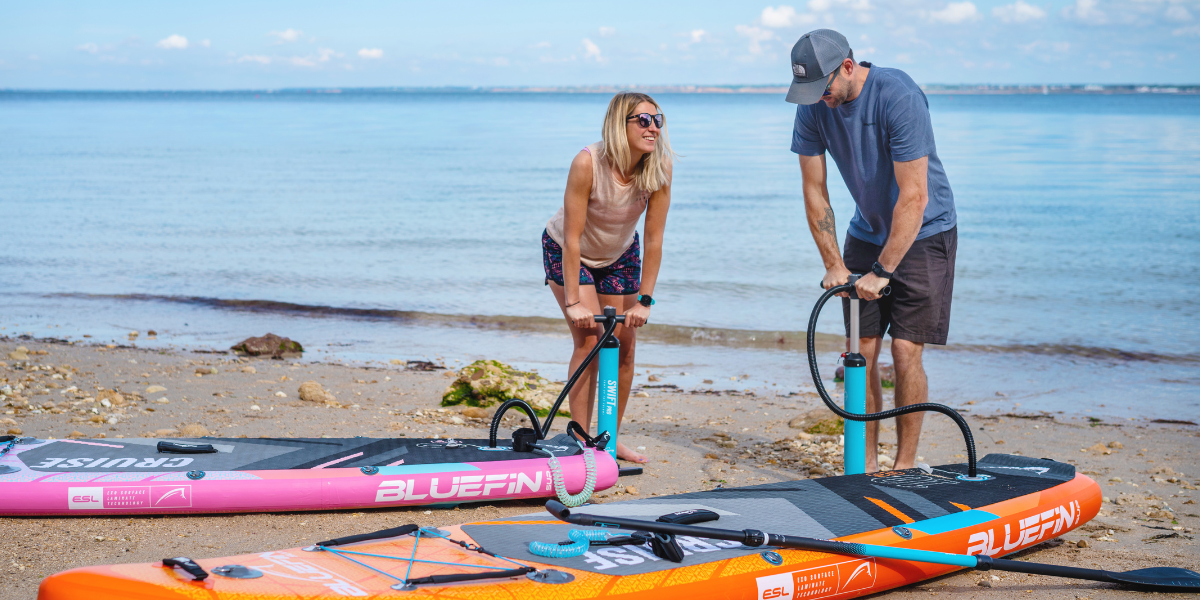 two people inflating paddle boards