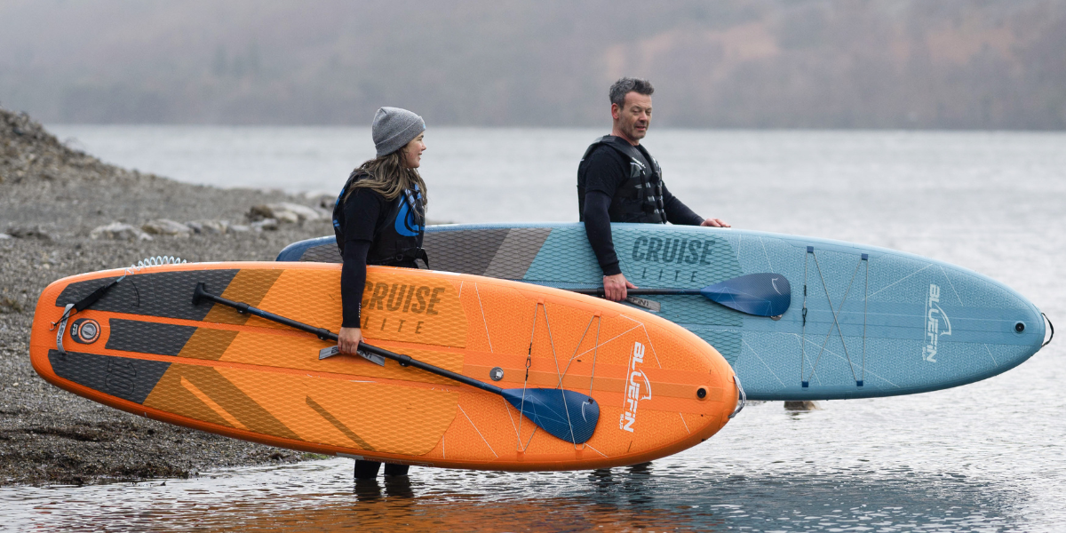 two people holding paddle boards