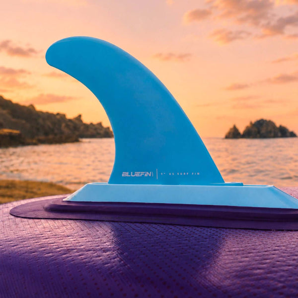 Bluefin surf fin in blue color mounted on a purple paddleboard with a sunset background