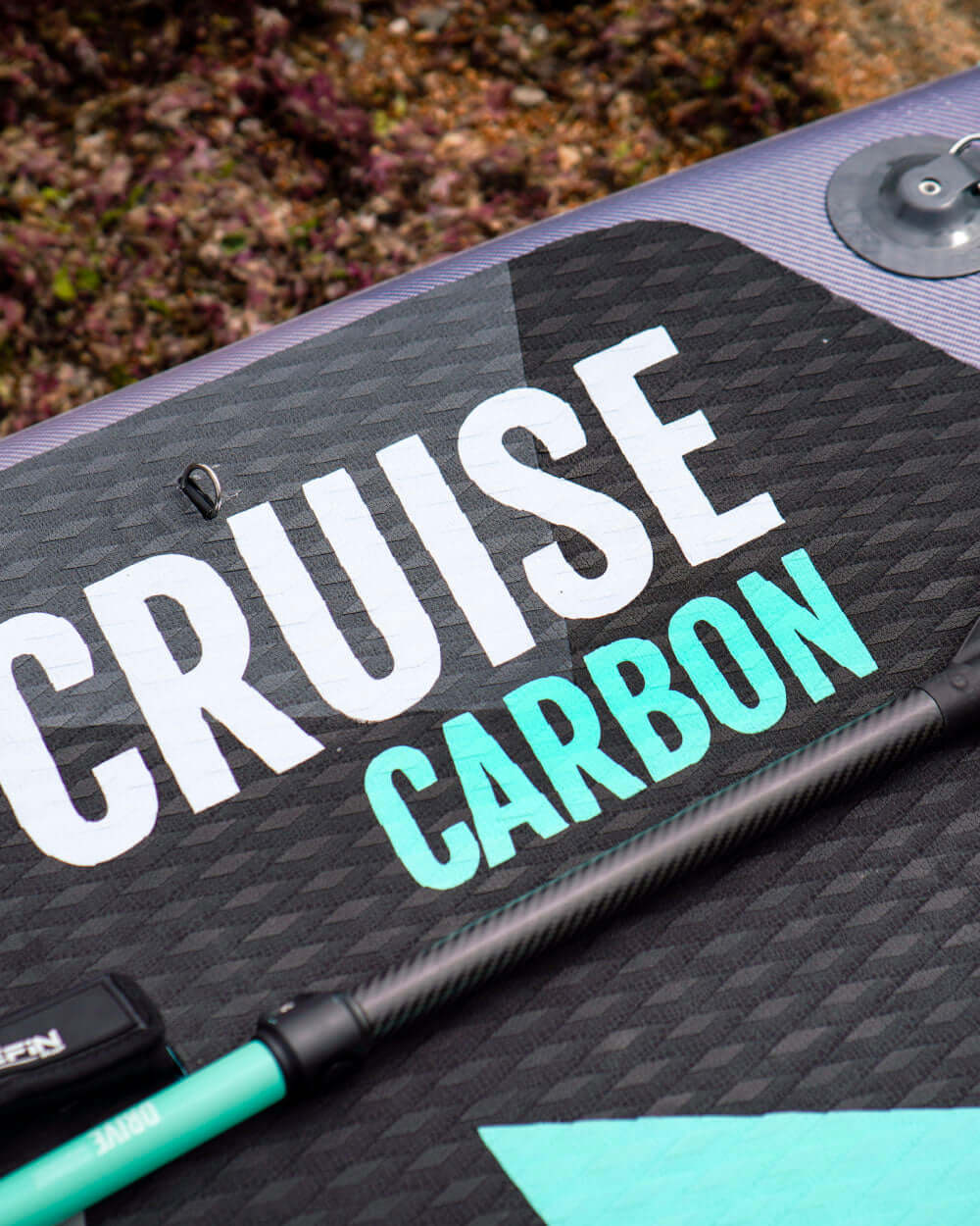 Paddleboard deck featuring the words "CRUISE CARBON" and a carbon fiber paddle beside it