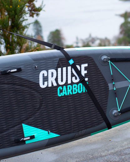 Close-up of a cruise carbon paddle board being held by the bluefin sup carry strap on a cloudy day.