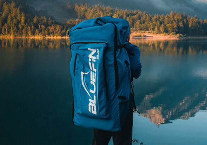 Bluefin SUP backpack against a serene lake backdrop, ideal for outdoor adventures.