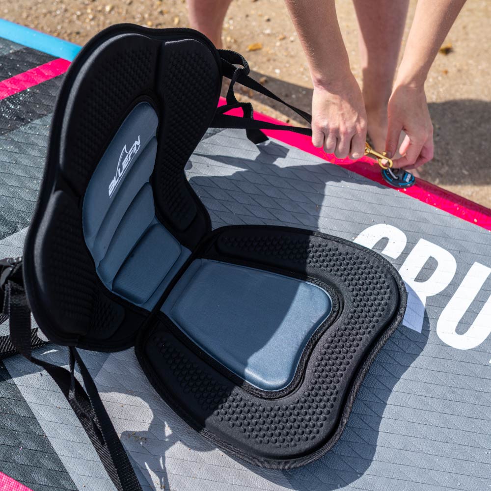 Comfortable Bluefin SUP seat cushion on a paddleboard with a person securing the strap.
