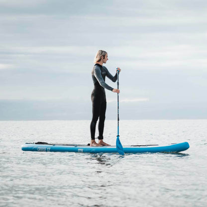 Person paddleboarding on a blue SUP in calm water under a cloudy sky.