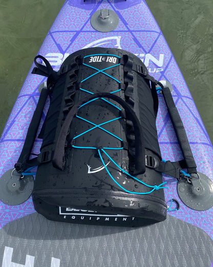 Black dri-tide backpack with blue bungee straps on a purple inflatable paddle board
