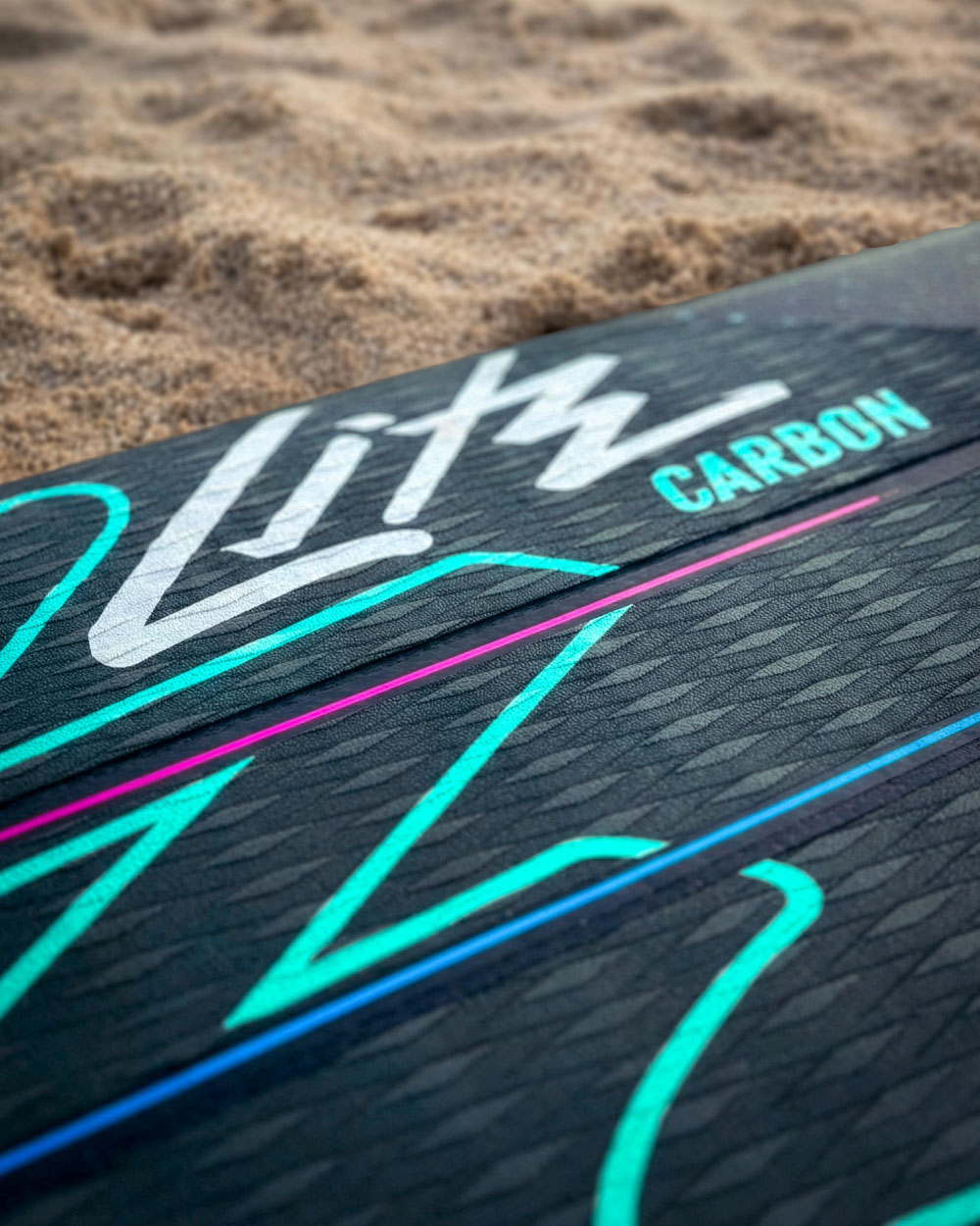 Close-up of a black paddleboard deck with colorful graphics and the word 'Carbon