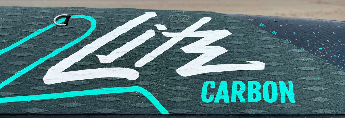 Textured paddleboard deck with white 'Litz' logo and 'CARBON' in turquoise