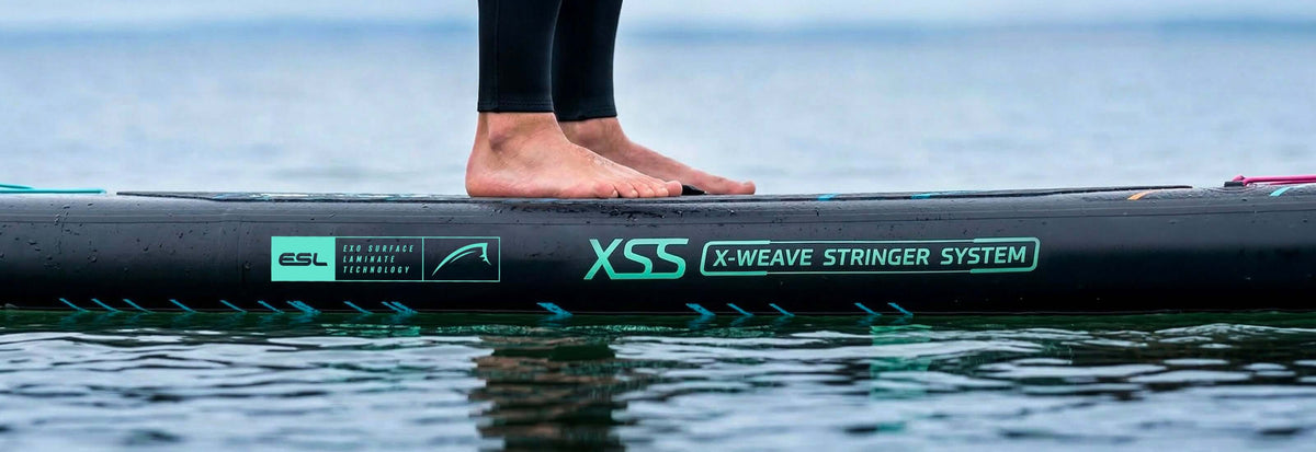 Inflatable paddleboard with bare feet standing on it, featuring X-Weave Stringer System and ESL branding