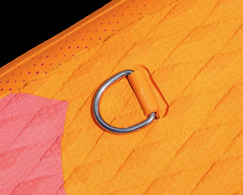 Close-up of an orange textured surface with a pink section and a silver D-ring attachment