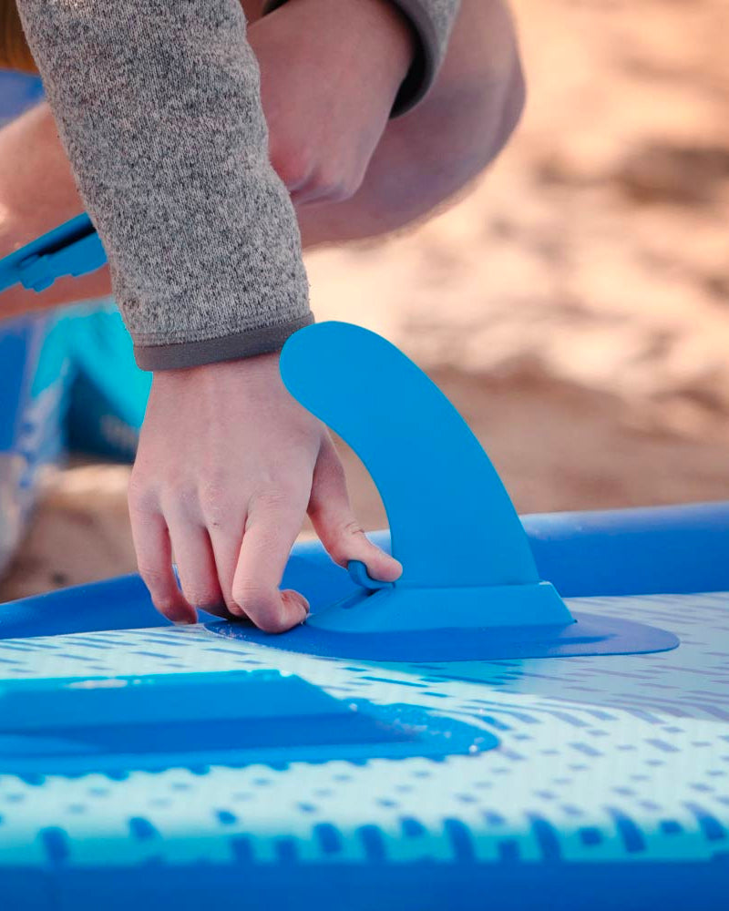 someone attaching a bluefin smartlock fin to an inflatable sup
