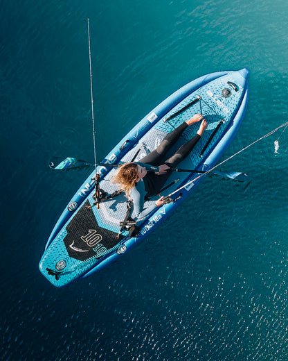 Person fishing on a voyage 10'10 blue paddle board in clear water