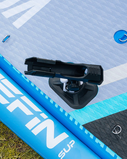 Close-up of a stand-up paddleboard with a mounted fishing device on a grassy background