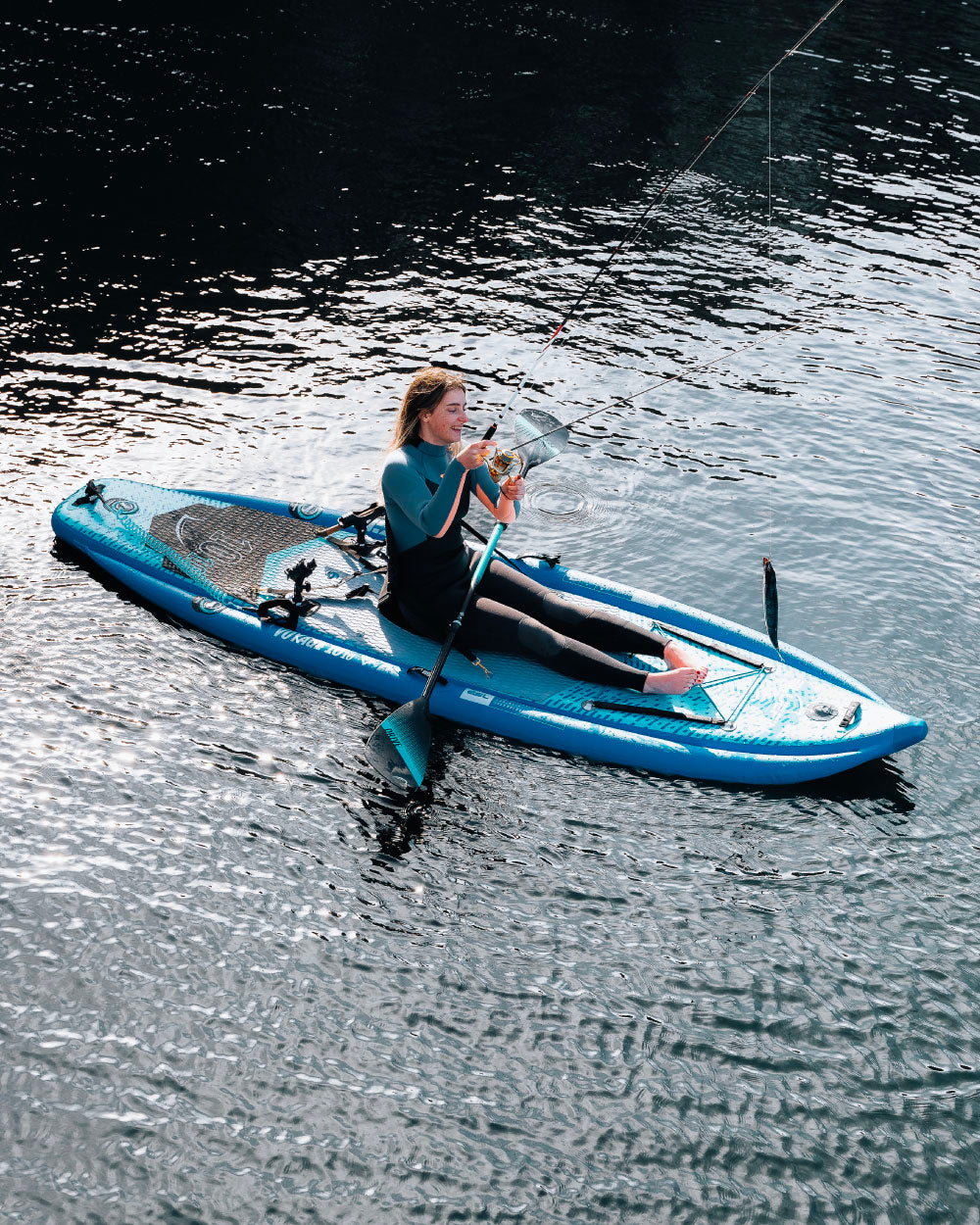 Person paddleboarding on a blue board in calm water