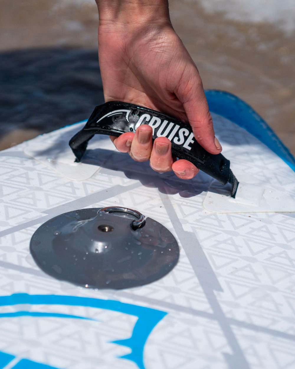 Hand holding a black carry handle handle with 'Cruise' branding on a paddleboard
